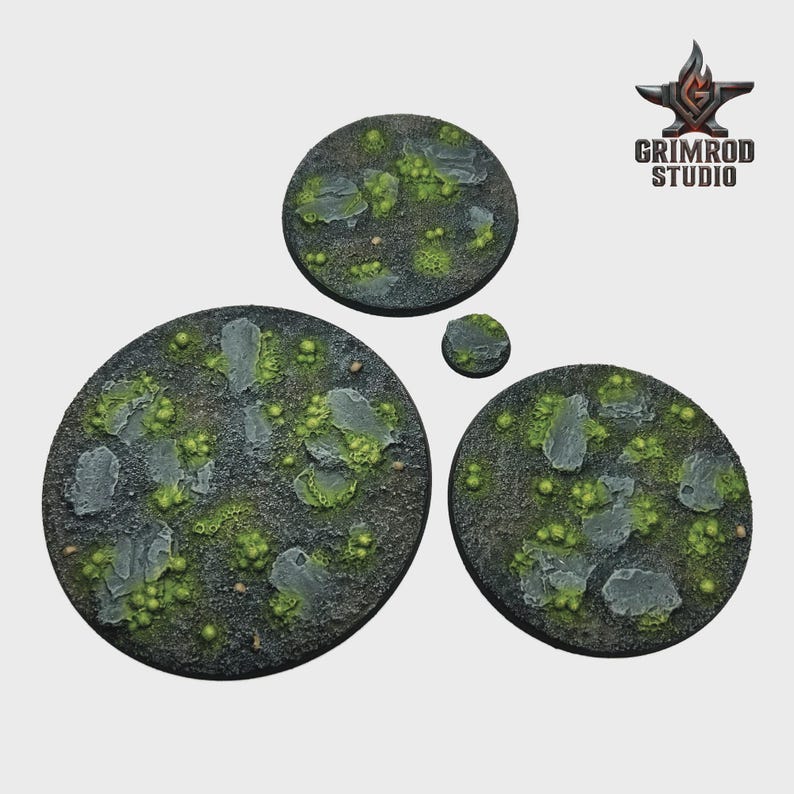 May include: Four circular miniature bases with a textured, rocky surface. The bases are painted in shades of gray, green, and brown, with detailed rock and moss elements. The Grimrod Studio logo is in the upper right corner.