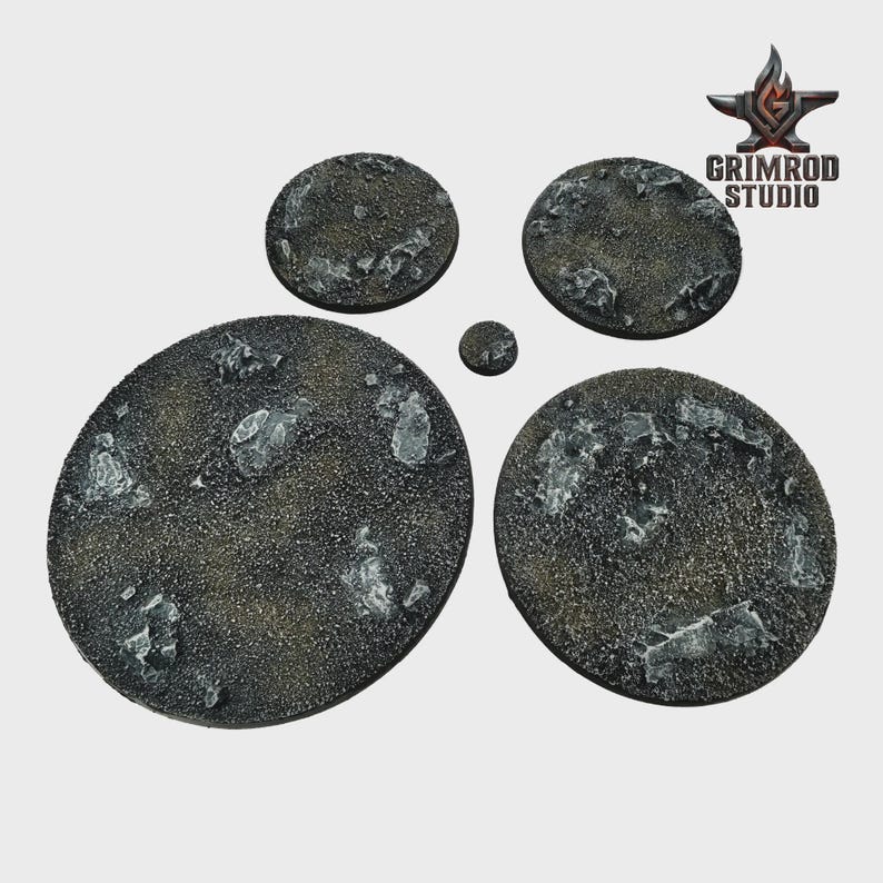 May include: A collection of textured, circular bases in varying sizes, designed for miniature figures. The bases have a dark, speckled surface with embedded, irregular, light-colored rock formations. The Grimrod Studio logo is visible in the upper right corner.