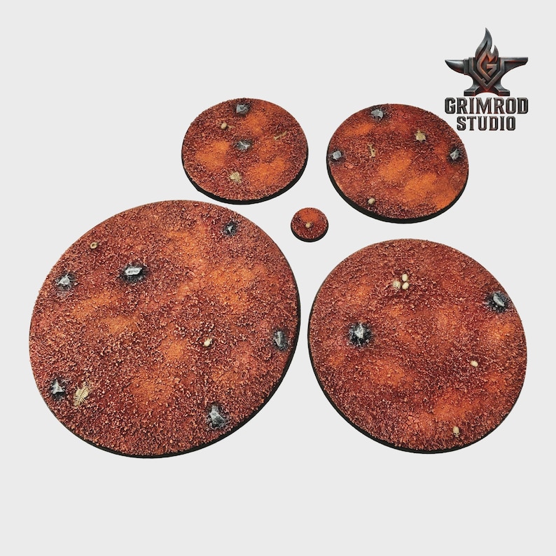 May include: A collection of textured, circular bases in varying sizes, featuring a reddish-brown color scheme with embedded metallic and stone-like details. The bases are designed for miniature figures, with the Grimrod Studio logo visible in the upper right corner.