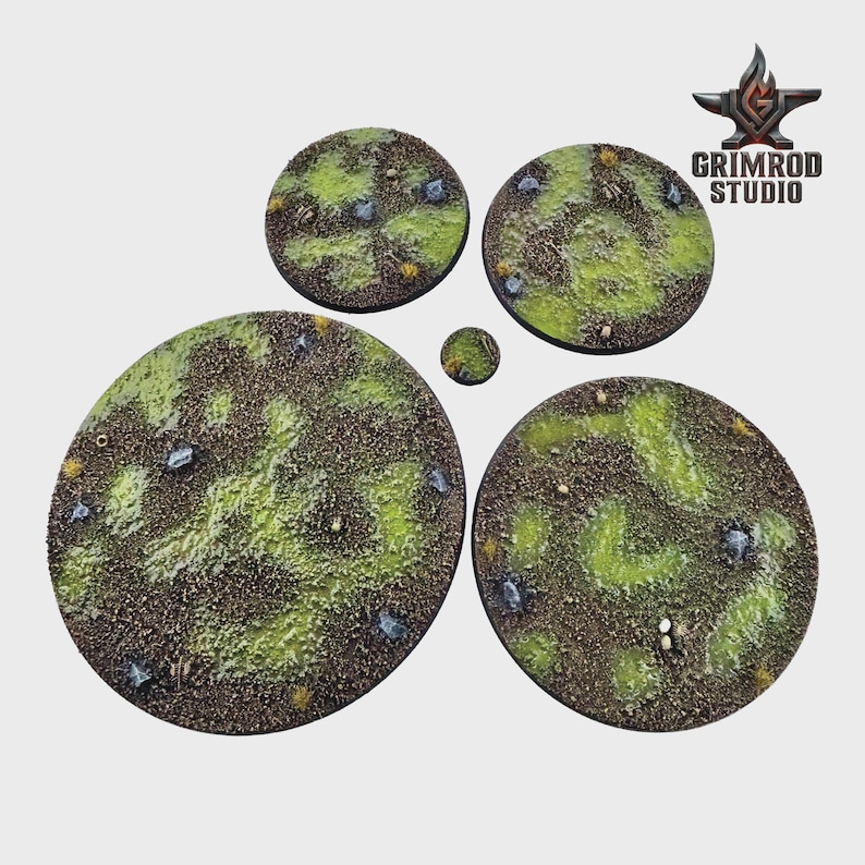 May include: A collection of five circular miniature bases with textured surfaces. The bases feature a mix of brown, green, and gray tones, with small rocks and patches of grass. The Grimrod Studio logo is visible in the upper right corner.