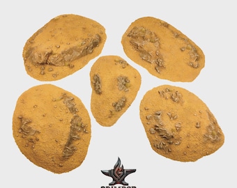 May include: Five irregular, tan-colored terrain bases with textured, rocky surfaces and sandy ground details. The pieces feature raised ridges and uneven elevations, designed for miniature displays. The Grimrod Studio logo is printed at the bottom.