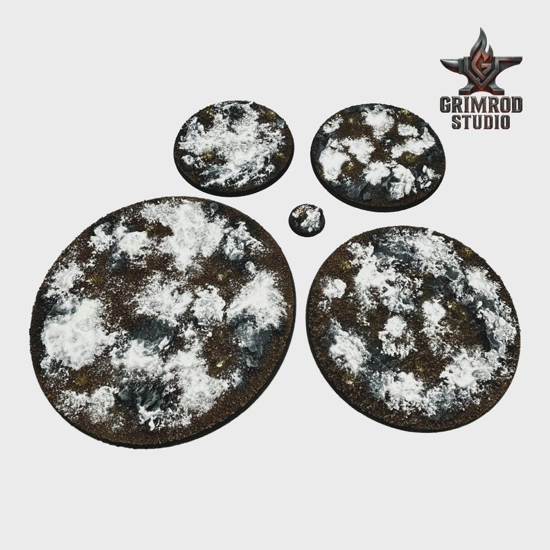 May include: A collection of miniature bases with a snow-covered terrain effect. The bases are various sizes, ranging from small circles to larger ovals. The bases are brown with white and gray accents, and the Grimrod Studio logo is in the upper right corner.