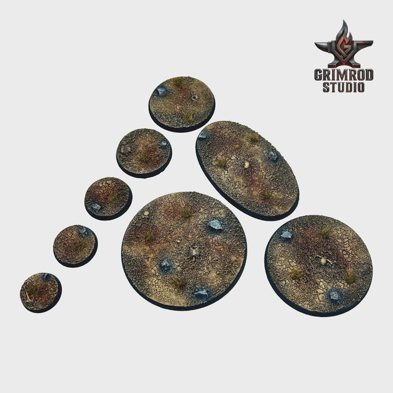 May include: A collection of textured, brown miniature bases in various shapes and sizes, including round and oval. The bases feature a cracked earth design with small rocks and sparse vegetation. The Grimrod Studio logo is in the upper right corner.