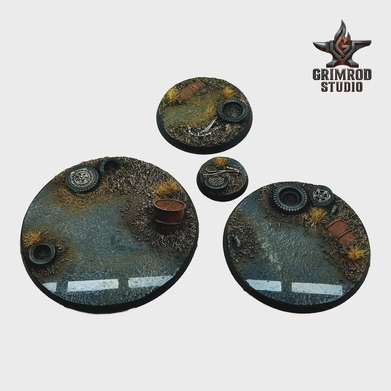 May include: Four circular miniature bases with a post-apocalyptic theme. The bases feature a road surface with white lines, patches of dry grass, and debris like tires and barrels. The Grimrod Studio logo is in the upper right corner.