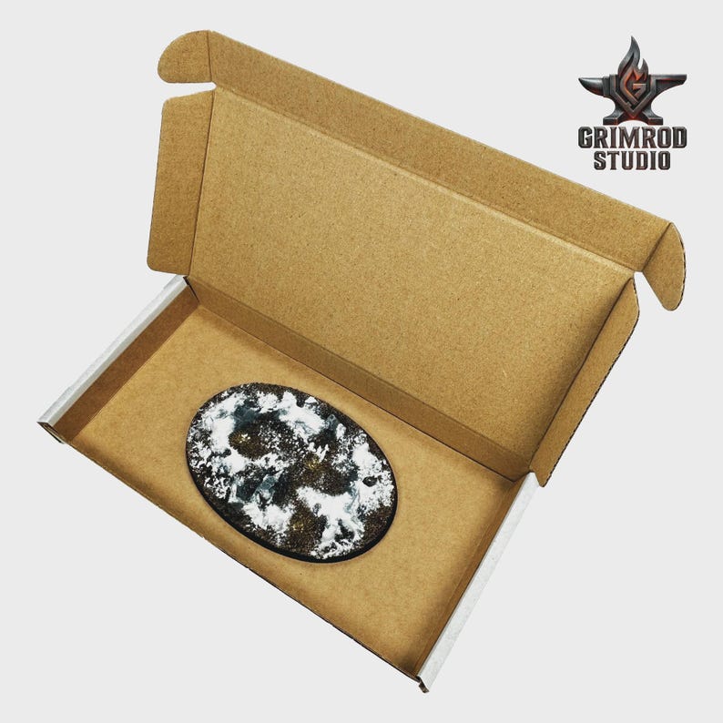May include: An oval-shaped, abstract art piece with white, black, and gold accents, presented inside a brown cardboard box. The box is open, revealing the artwork. The Grimrod Studio logo is visible in the upper right corner.