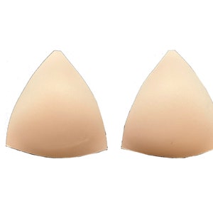 Pode incluir: Duas copas de sutiã triangulares de cor nua feitas de espuma.