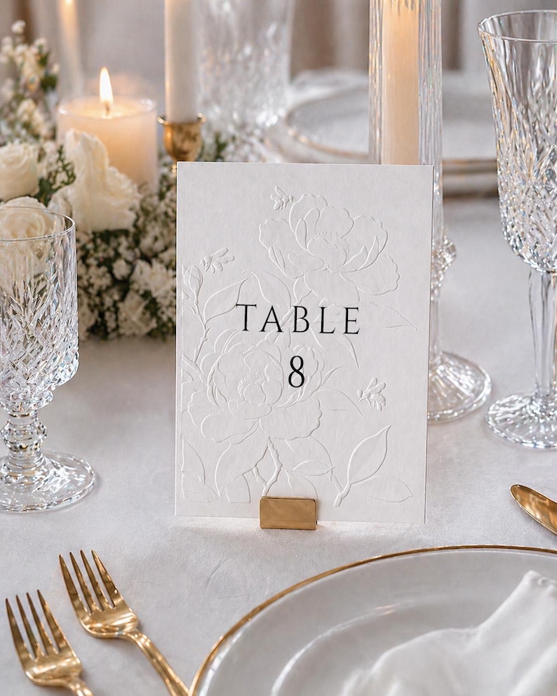 Minimalistische und elegante Tischnummern für Hochzeit & Event auf hochwertigem handgeschöpftem Büttenpapier in Weiß oder Ivory. Veredelt mit floraler Blindprägung und edlem Digitaldruck, wählbar in 3 stilvollen Farben. Die Fine-Art Tischkarten schaffen eine luxuriöse und zeitlose Tischdekoration für moderne Hochzeiten, Dinner, Gala oder exklusive Feiern. Ideal für Brautpaare, die elegante Papeterie, hochwertige Hochzeitsdeko und individuelles Design lieben.