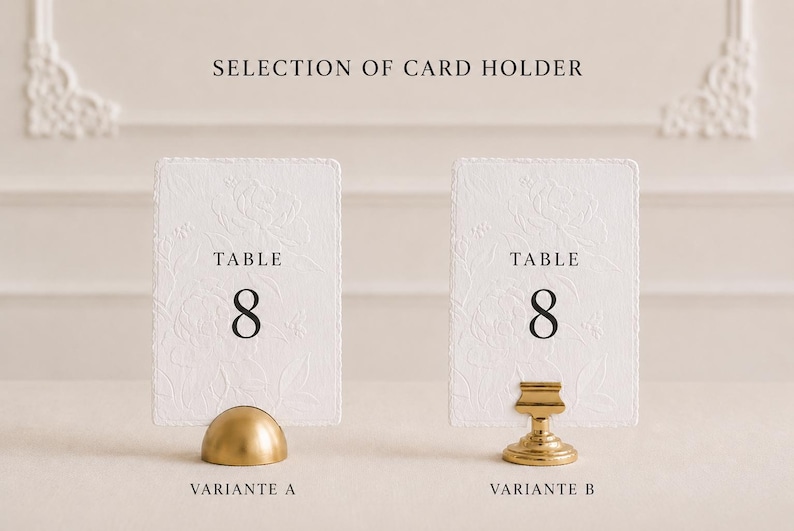 Puede incluir: Dos tarjetas rectangulares blancas de n&uacute;mero de mesa con patrones florales en relieve y el texto TABLE 8 en negro. La tarjeta de la izquierda se sostiene con un soporte dorado en forma de c&uacute;pula etiquetado VARIANTE A, y la de la derecha con un soporte de pedestal dorado VARIANTE B.