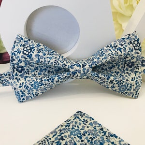 Può includere: Un papillon bianco con un motivo floreale blu e un fazzoletto da taschino abbinato.