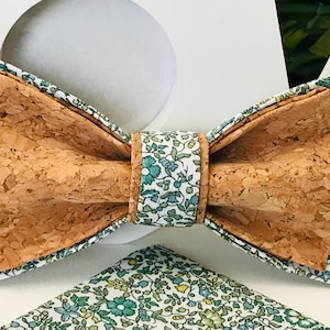 Peut inclure: Un nœud papillon en liège brun avec un motif floral blanc et vert. Le nœud papillon est fait de liège et de tissu.