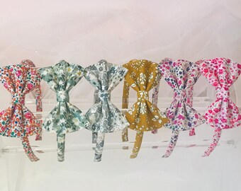 May include: Six floral print headbands with bow details. The headbands are in various colors, including pink, green, yellow, and blue.