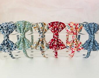 May include: Six floral patterned fabric headbands with bow accents. The headbands are in various colors, including blue, green, white, brown, red, and orange.
