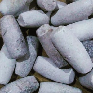 Könnte beinhalten: Ein Haufen glatter, grauer, zylindrischer Steine. Die Steine sind in verschiedenen Größen und Formen, und einige haben eine leicht strukturierte Oberfläche.