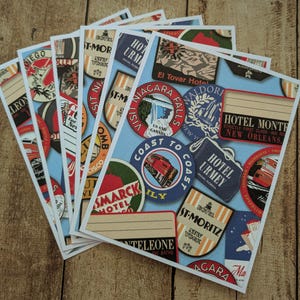 May include: A collection of travel-themed postcards featuring vintage-style illustrations. The postcards showcase various destinations with colorful designs, including hotel labels, city names, and travel-related imagery. The postcards are arranged on a wooden surface.