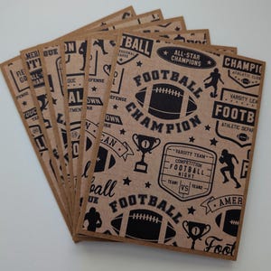 May include: A stack of kraft paper cards with a repeating black graphic design. The design includes footballs, trophies, stars, and text that reads "Football Champion," "All-Star Champions," and "Varsity Team."