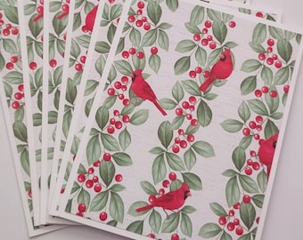 May include: A set of six blank greeting cards with a red cardinal and holly berry pattern. The cards are white with a white border.