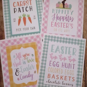 May include: Four printable Easter signs with a gingham background. The signs feature the text "Carrot Patch", "Hippity Hoppity Easter's on its way!", "All you need is love & Easter Candy", and "Easter hop hop hop Egg Hunt Colored Eggs Baskets chocolate bunnies".