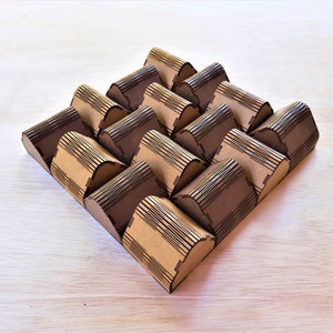 May include: A geometric decorative object made from interlocking arched pieces. The pieces are made of light brown and dark brown cardboard, arranged in a diamond shape. The object is on a light wood surface.