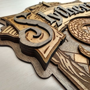 May include: Wooden Slytherin house crest, featuring a detailed snake, the letter "S", and the house name. The layered design uses natural wood tones and intricate laser-cut details, creating a dimensional effect. The overall aesthetic is rustic and detailed.