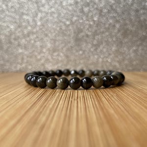 K&ouml;nnte beinhalten: Ein Armband aus schwarzen und goldenen Perlen mit runden Perlen.