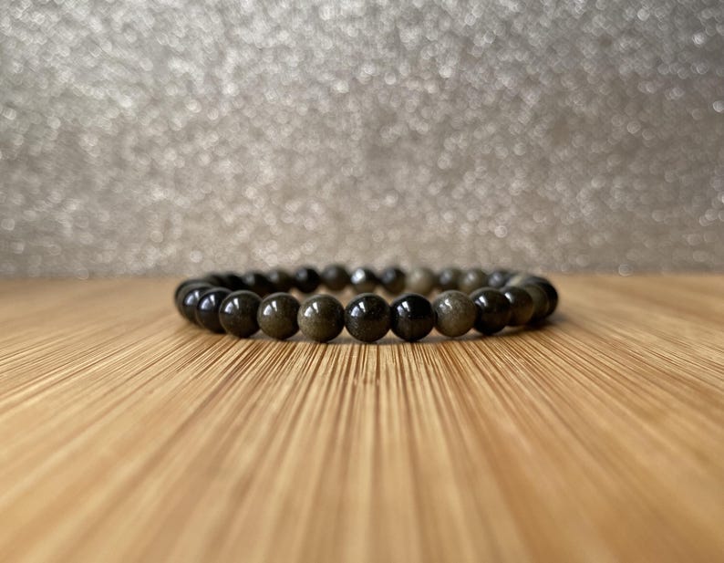 K&ouml;nnte beinhalten: Ein Armband aus schwarzen und goldenen Perlen mit runden Perlen.