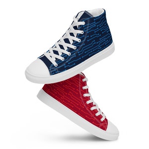 Peut inclure: Une paire de baskets montantes en toile avec une semelle blanche et un motif de circuit imprimé bleu et rouge. La basket bleue est sur la basket rouge.