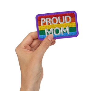 Może przedstawiać: Fioletowa łatka z tęczowym wzorem i napisem "PROUD MOM" w kolorze białym.