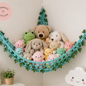 May include: A light blue crocheted hammock filled with various plush toys, including a teddy bear, bunny, and several smaller stuffed animals. The hammock is decorated with green leaves and is mounted on a white wall. The image includes the text "Handmade with Love".