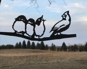 May include: Black metal silhouette of a cardinal and three small birds perched on a branch. The birds are facing different directions, creating a dynamic composition.