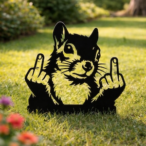 Puede incluir: Adorno de jardín de metal negro con una ardilla haciendo la peineta. La ardilla está sentada con los brazos levantados. El adorno está colocado en una zona de césped con flores en primer plano.