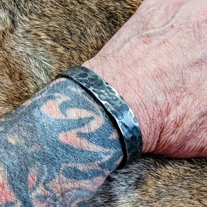 May include: A silver hammered metal bracelet with a textured finish.