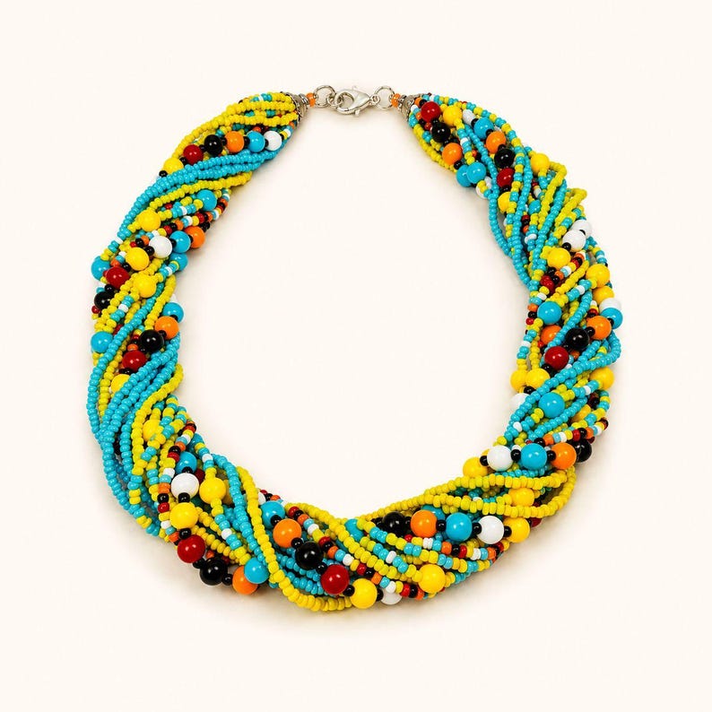 May include: A multi-strand necklace featuring twisted rows of small beads in vibrant shades of yellow, turquoise, red, orange, black, and white. The necklace is secured with a silver-toned metal lobster claw clasp at the top center.