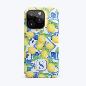 May include: A white phone case with a blue and yellow pattern of lemons and floral designs. The case has a cutout for the camera lens and a blue letter "S" in the center.