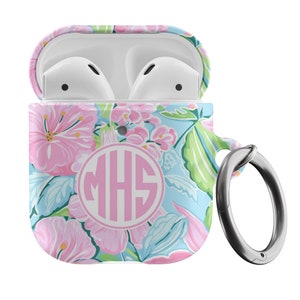 Puede incluir: Una funda blanca para Airpods con un diseño floral en rosa, azul y verde. La funda tiene un monograma rosa "MHS" y un anillo de metal plateado.