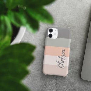 May include: A phone case with a striped design in shades of pink, gray, and white. The name "Chelsea" is written in cursive on the case.