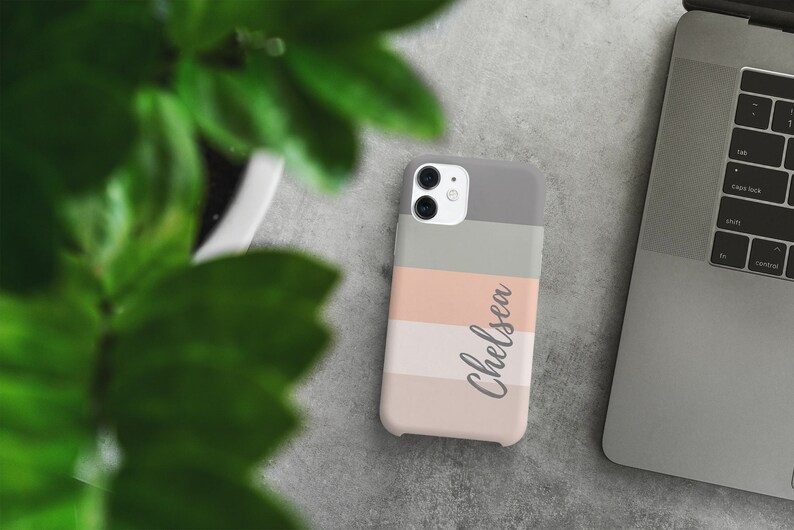 May include: A phone case with a striped design in shades of pink, gray, and white. The name "Chelsea" is written in cursive on the case.