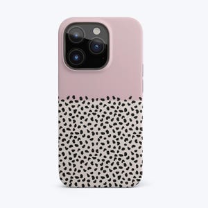 May include: A pink and white phone case with a black and white polka dot pattern. The case has a raised camera bump and a cutout for the phone's charging port.