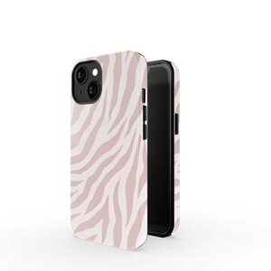 May include: A pink and white zebra print phone case with a black phone inside. The case is made of a hard plastic material and has a raised lip around the camera lens to protect it from scratches.