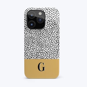 May include: A white and black polka dot phone case with a yellow bottom and the letter "G" in black.