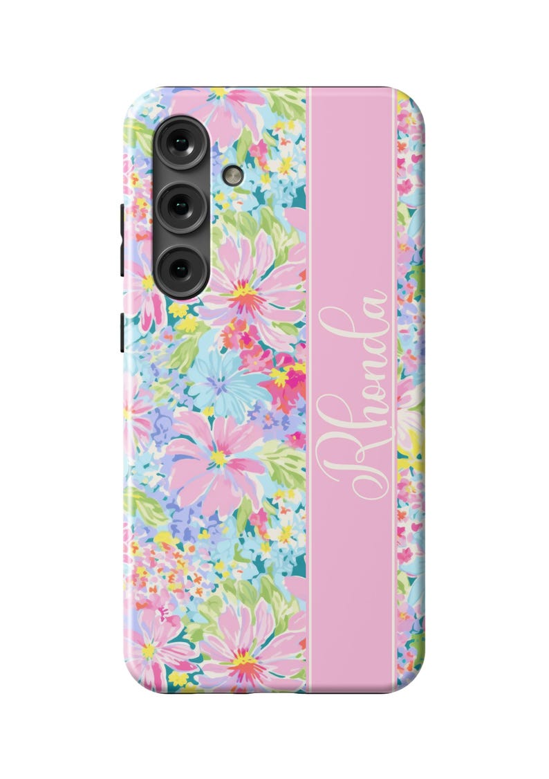 May include: A pink floral phone case with a pink stripe down the center and the name "Rhonda" written in white script.