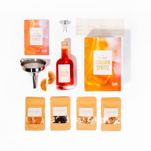 May include: An Italian Spritz cocktail kit with a bottle of red liquid, a funnel, dried orange slices, and packets of ingredients. The kit includes a recipe book with the text "Do Your Italian Spritz".