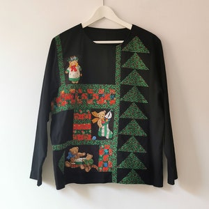 May include: Black long-sleeved shirt with a patchwork design featuring teddy bears and Christmas trees. The design is in shades of red, green, and white.