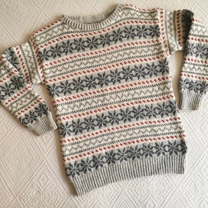 May include: A gray, white, and red patterned sweater with a crew neck.