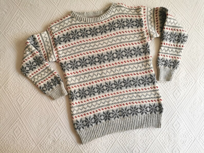 May include: A gray, white, and red patterned sweater with a crew neck.