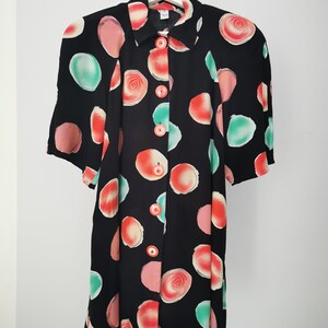 May include: A black button-up dress with a short sleeve and a colorful abstract print of red, pink, and green circles.