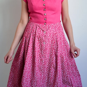 May include: A pink dress with a white floral print skirt and a solid pink bodice with a button-up front.