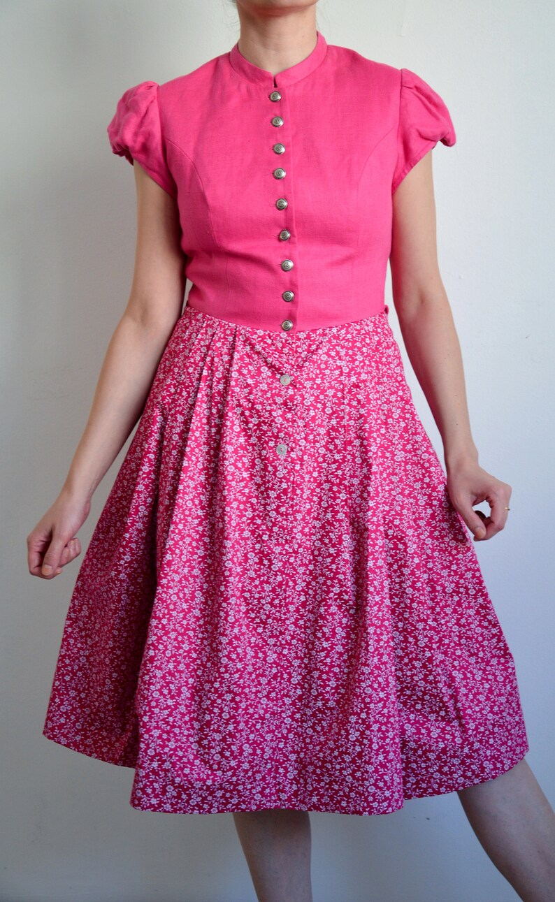 May include: A pink dress with a white floral print skirt and a solid pink bodice with a button-up front.