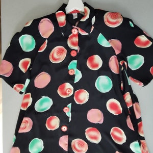 May include: A black button-up shirt with a short sleeve and a colorful abstract print of circles and swirls.