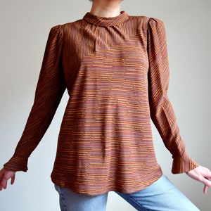 May include: A long-sleeved blouse with a high neck and a geometric pattern in shades of brown and orange.
