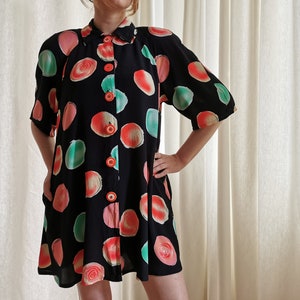 May include: A black short-sleeved button-up dress with a colorful abstract print of circles in shades of pink, green, and orange.